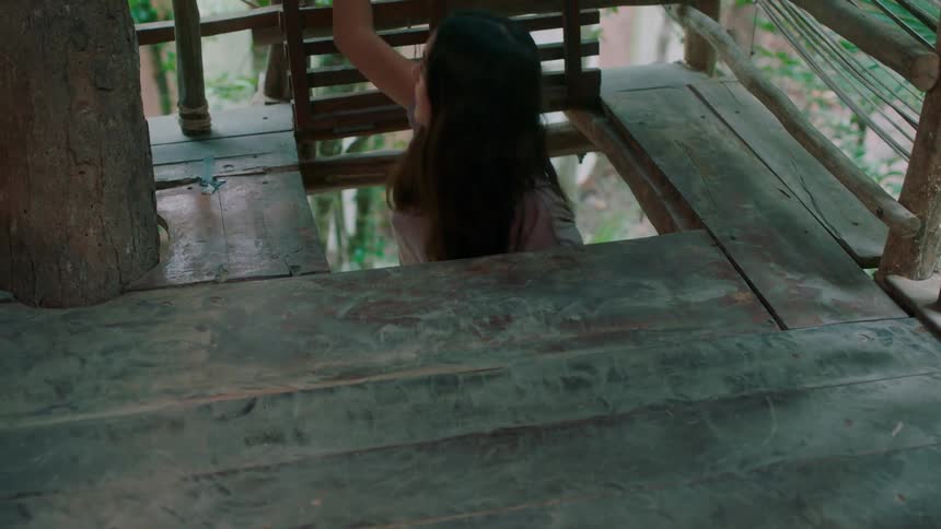 A woman climbs up into a tree house
