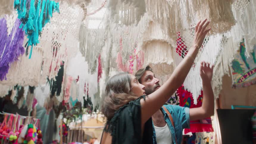 Man and woman look at dream catchers in a market