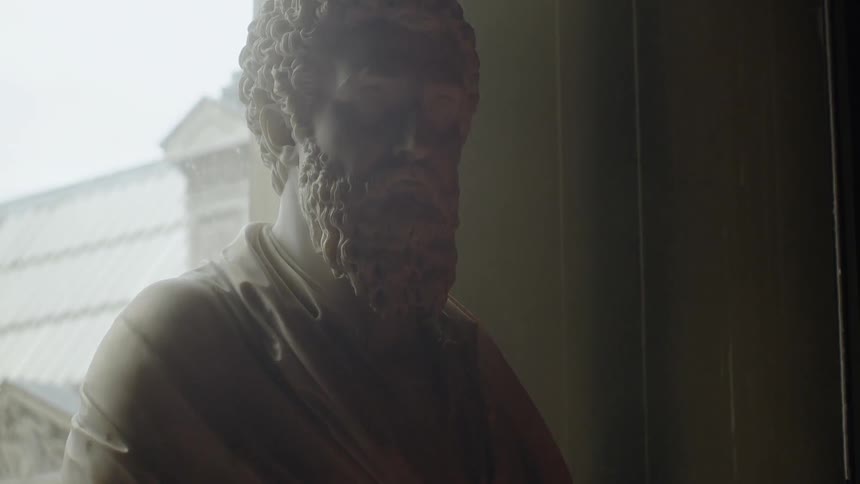 Statue of a bearded man stands next to a building