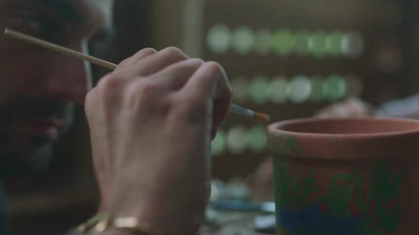 A man and woman paint clay pots