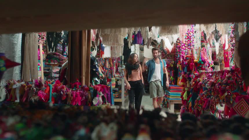 A man and woman walk in a market