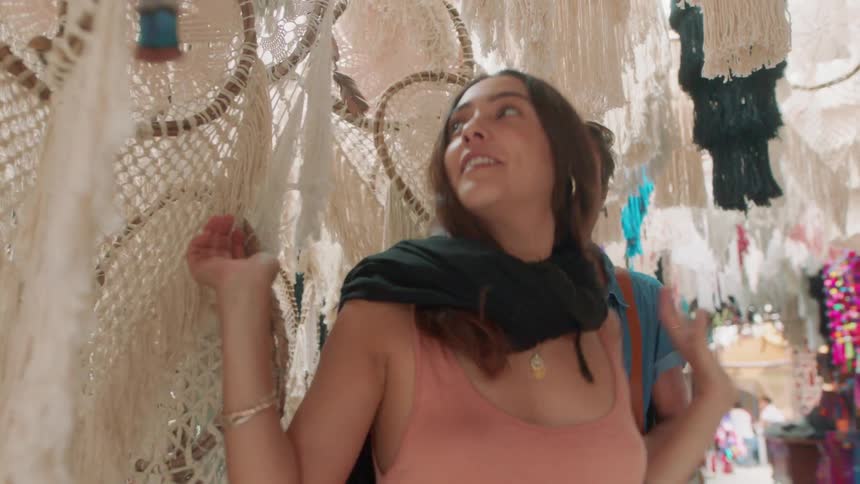 A man and woman walk through hanging dream catchers in a store