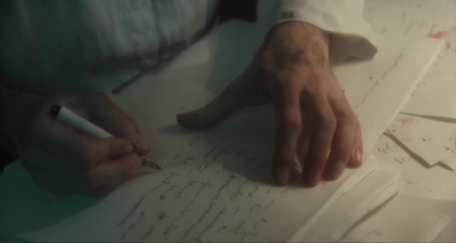 A person sits at a desk writing with a pen on paper