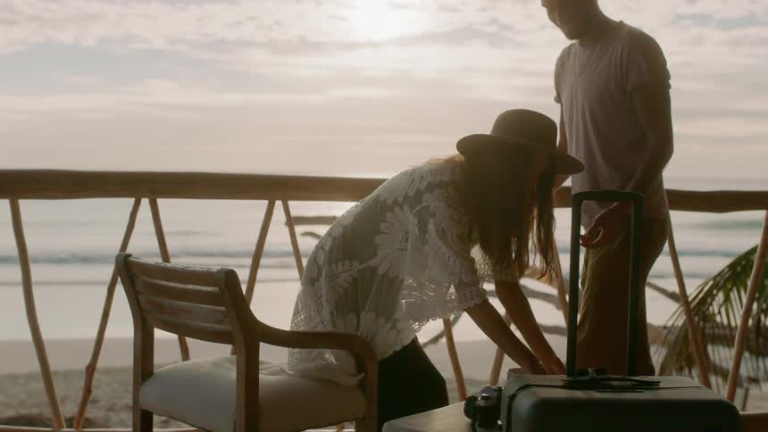A woman reading a book on the beach is greeted by a man