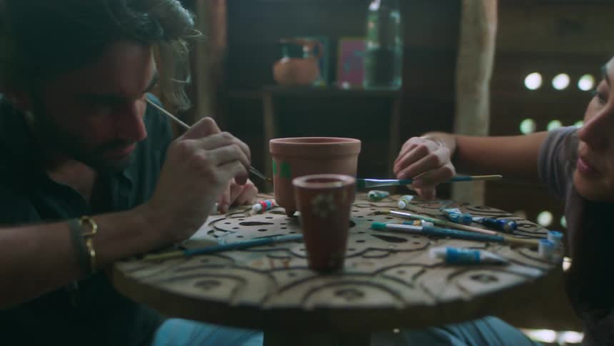 A man and woman paint clay pots