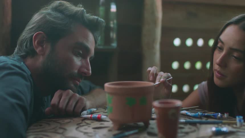 A man watches a woman panting a flower pot