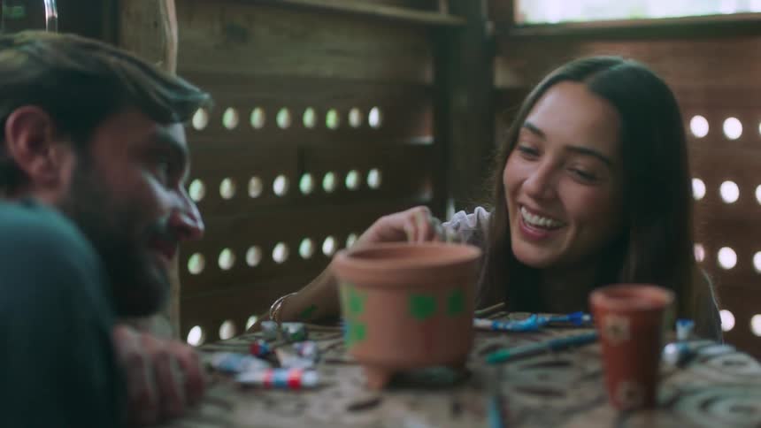 A man and woman smile while painting pottery