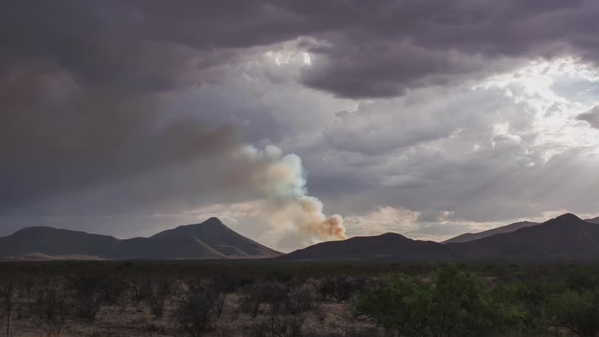 A fire burns beside mountains