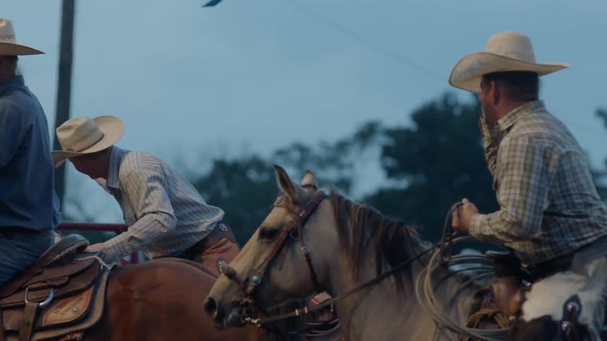 A group of cowboys riding horses greet each other