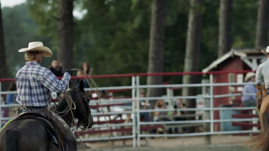Cowboys ride horses in a paddock