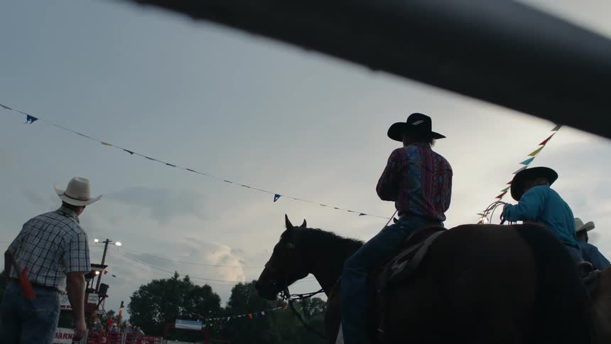The cowboys are riding on their horses and preparing lassos