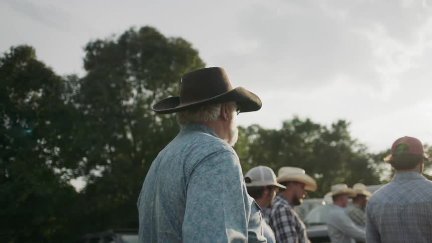 Cowboys are gathered outside near trees