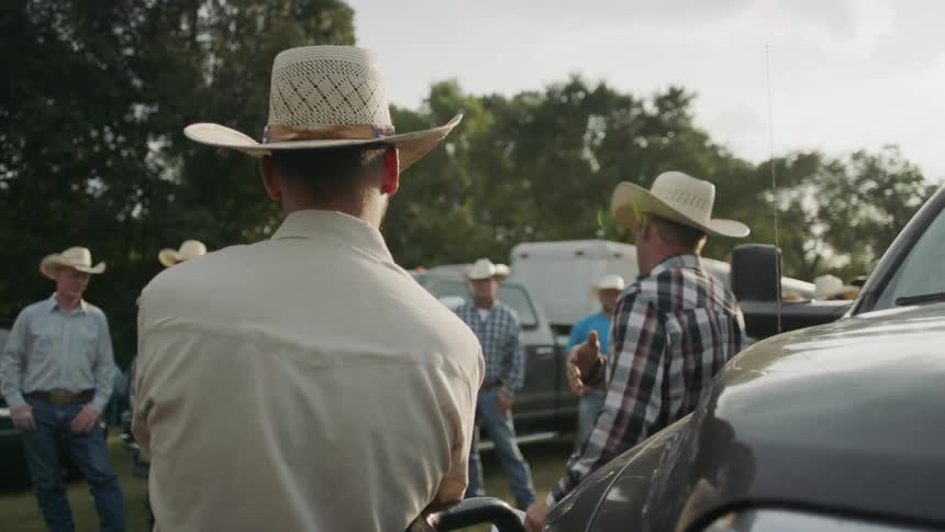 Cowboys are gathered outside near trucks