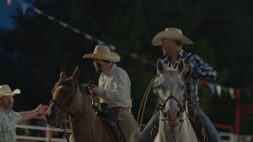 Cowboys ride on horses and carrying lassos