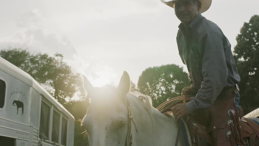 Man climbs into the saddle on a white horse and rides away