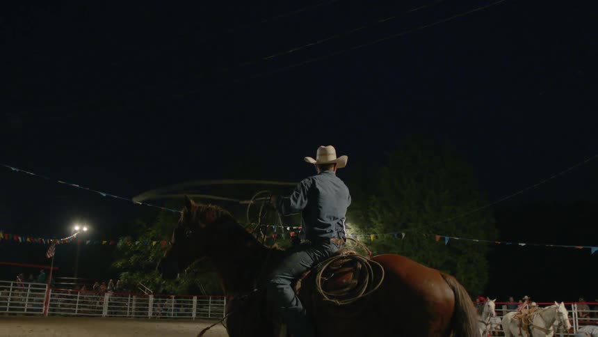 A bull roper swings his lasso