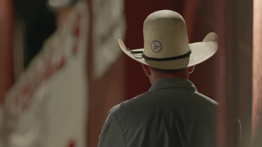 A man wears a cowboy hat outdoors