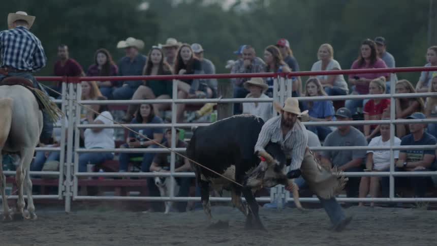 Two men rope a bull in a rodeo arena