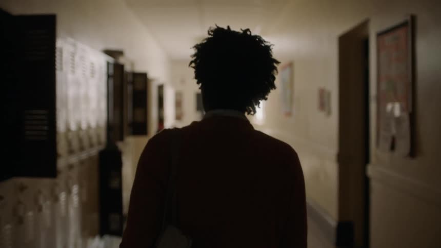 A man walks past lockers down a school hallway