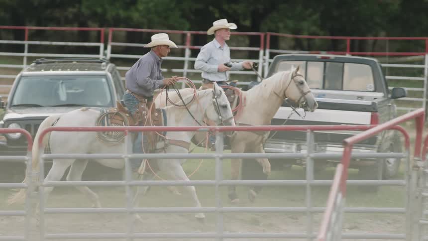 Cowboys ride horses on a ranch