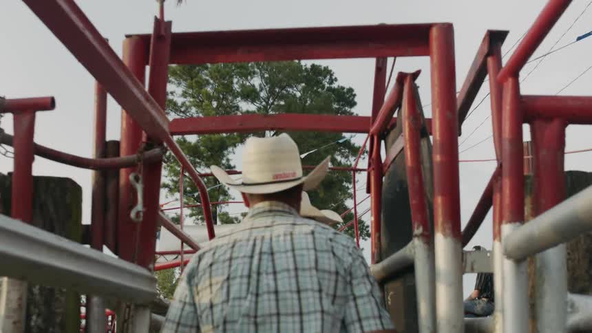 Cowboys walk through a gate