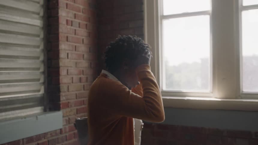 A woman enters a room with brick walls and appears nervous