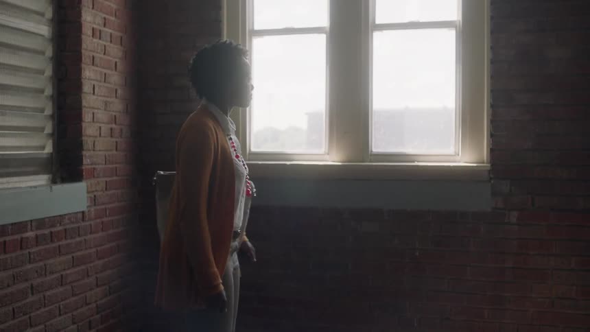 A woman looks nervous in a room with red brick walls