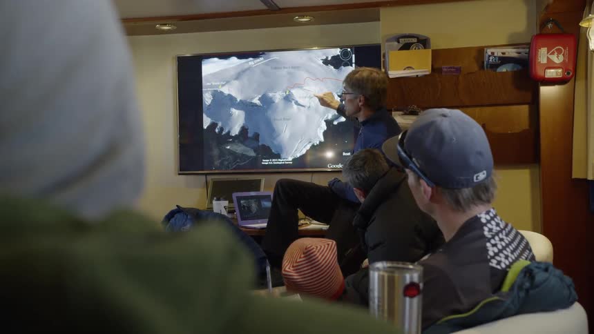 A group of people talk in the cabin of a boat