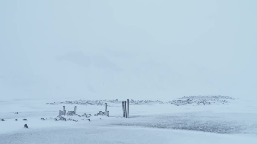 Posts and rocks stick out of the snow covered ground