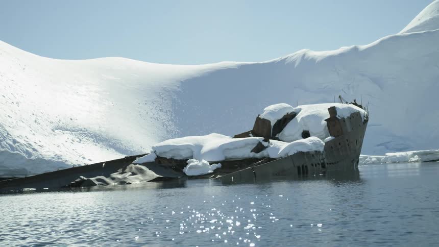 Water flows by a sunken ship covered in snow and ice
