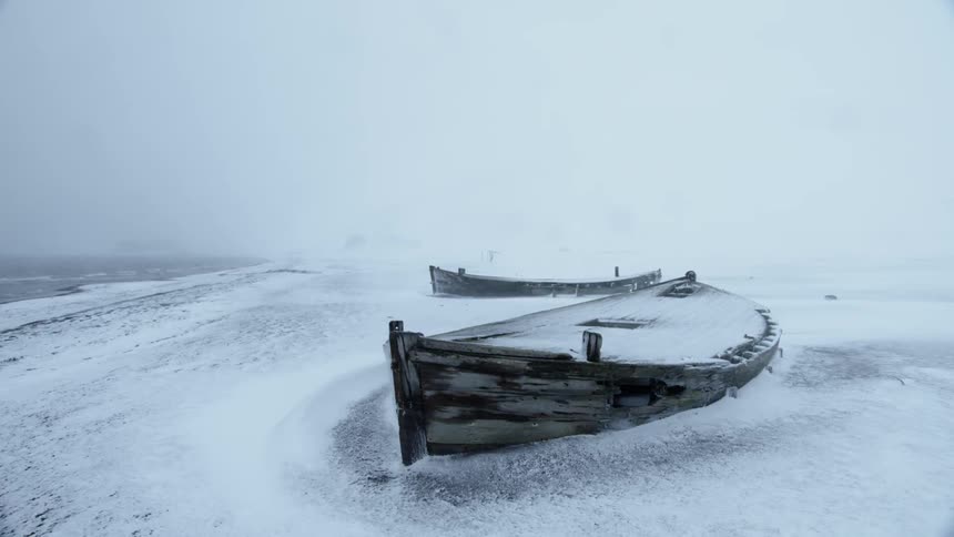 Abandoned desolate wooden boat in snow storm