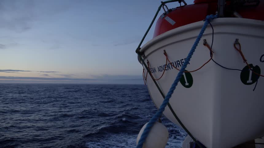 A life boat rocks on the water at sunset