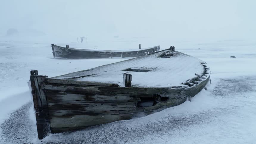 Row boats frozen in ice get covered in snow