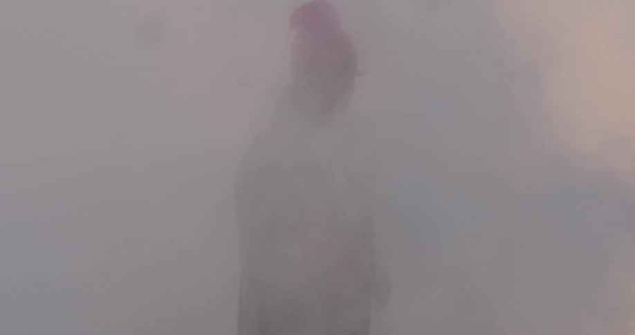 Man wearing a toque and long coat dances in the smoke