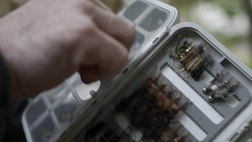 A fisherman chooses a hook from a case