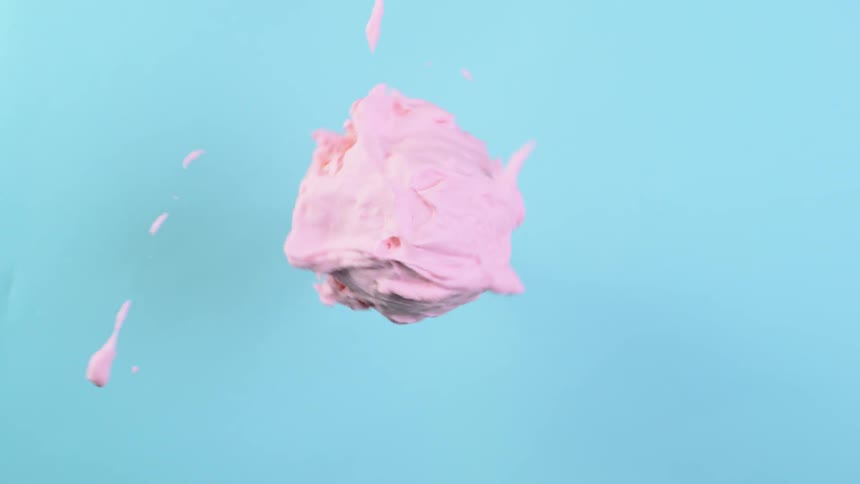 A scoop of ice cream is spinning in a circle throwing off streams of cream