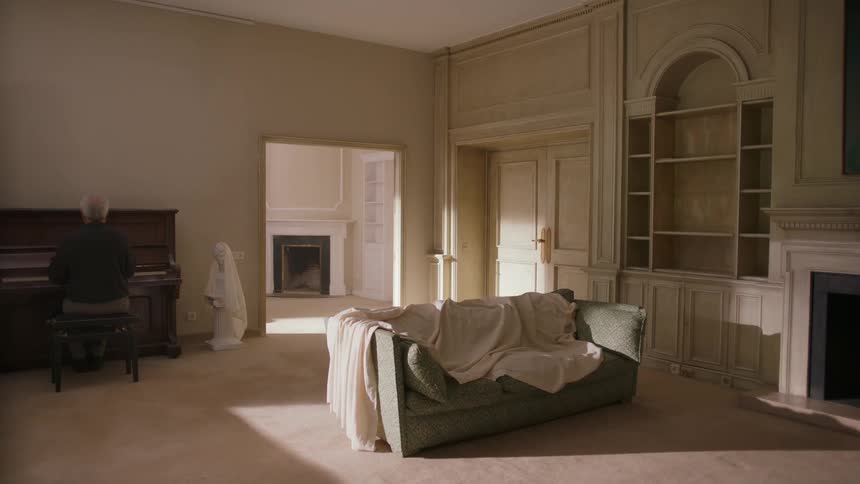 A man sits at a piano in a living room