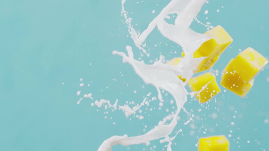 Diced mango fruit is thrown through falling white liquid