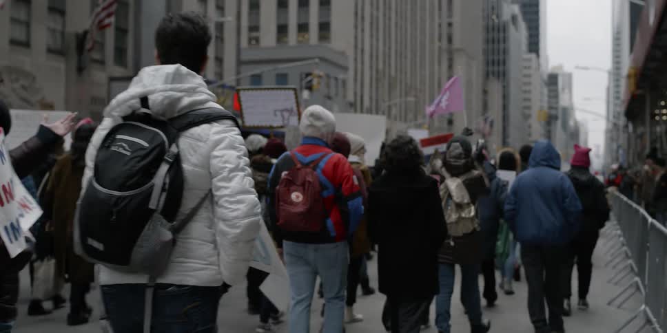 Group of people walk down a city street holding signs