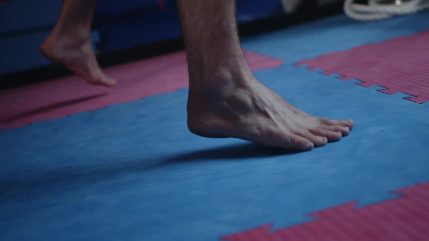 A barefoot man stands on gym mats