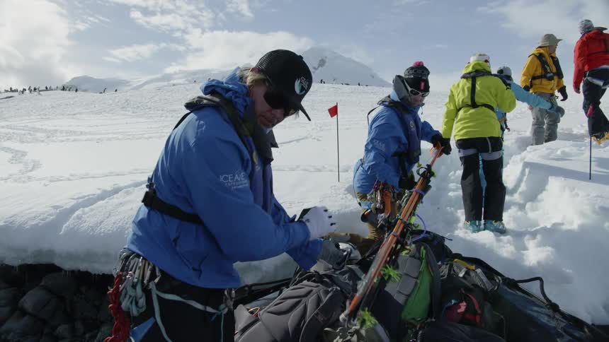People unload skis from a rubber zodiak