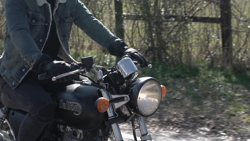 Man rides a motorcycle next to a field