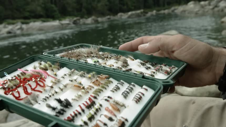 A fisherman holds a container of fish hooks
