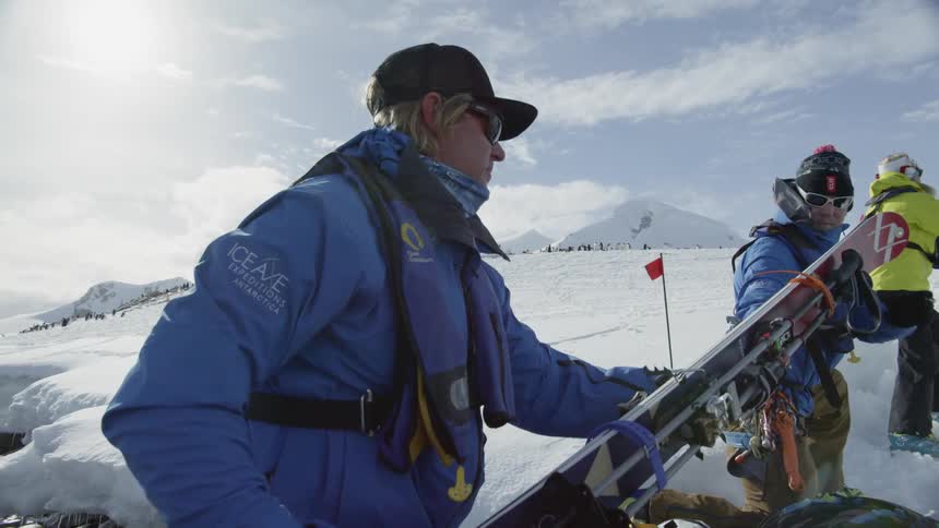 Skiers pass along equipment in snowy mountains