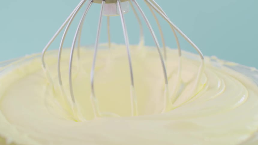 A stand mixer whisks icing