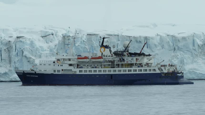 A ship floats off a snowy coast