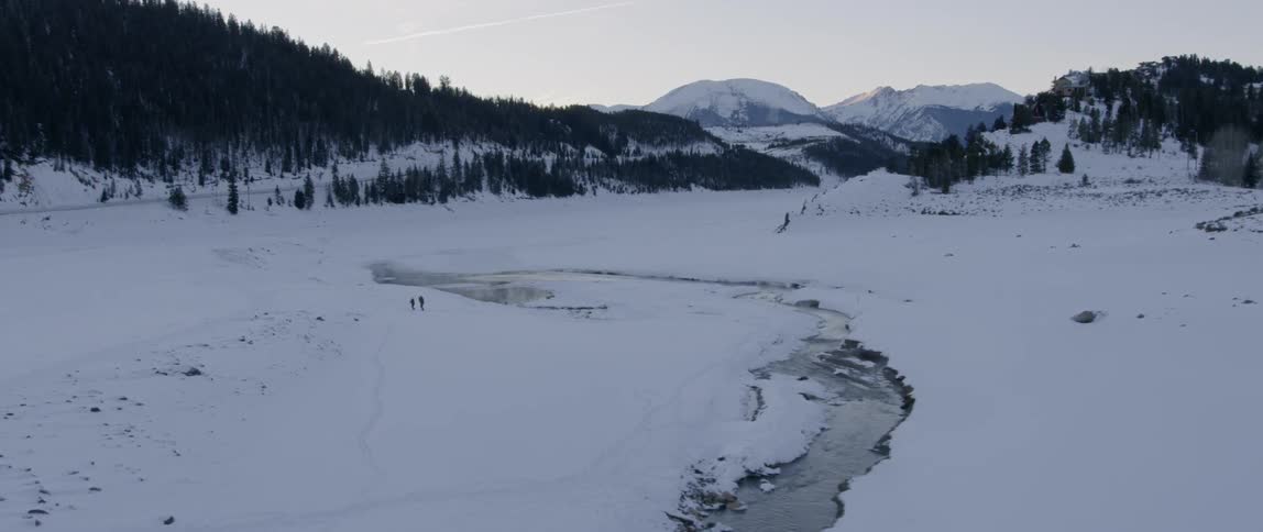 Hikers walk across a snowy landscape