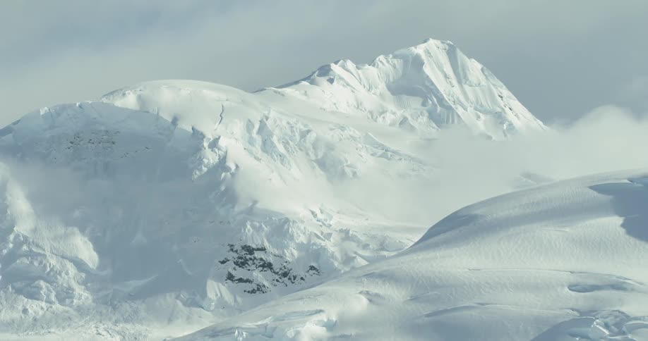 A glacier melts off of large snowy mountain