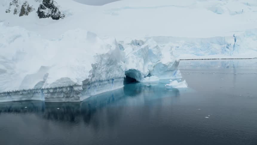 A small shelf of ice sits on the shore of the water