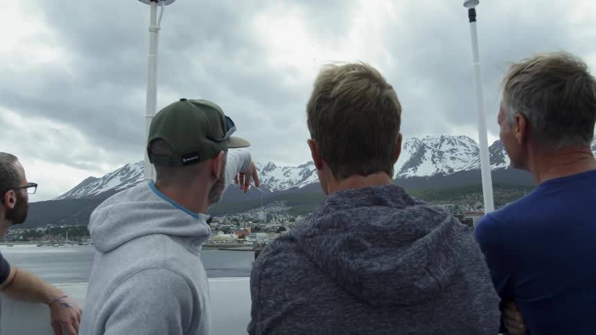 Men look and point towards snowy mountains